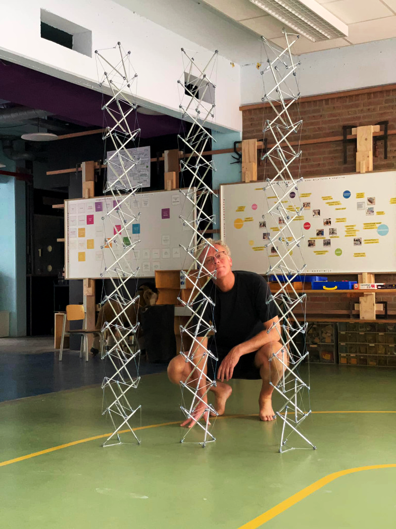 Gerald crouching with three tall vertical tensegrity pieces.